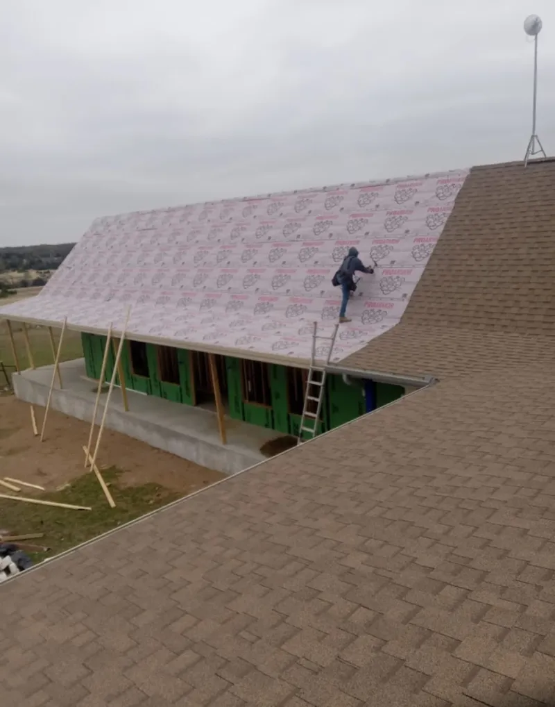 Worker preparing underlayment for a metal roof installation in Covington